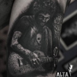 Человек в татуировках с гитарой на плече