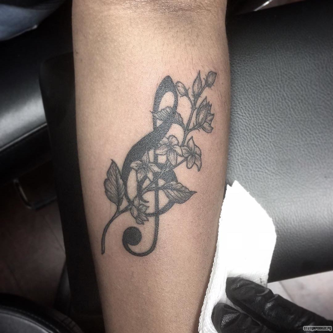 Фотография татуировки под названием «Скрипичный ключ с веткой цветов»