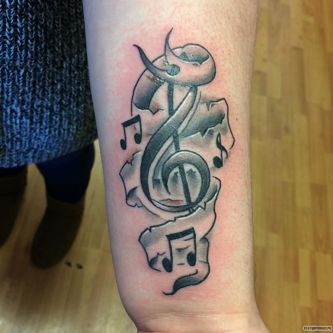 Фотография татуировки под названием «Скрипичный ключ в ленте с нотой»