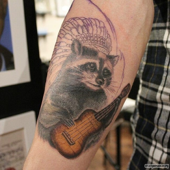 Фотография татуировки под названием «Енот с гитарой»