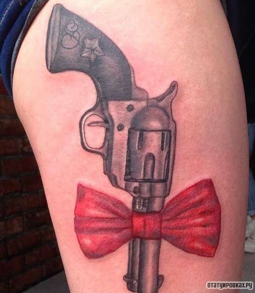 Фотография татуировки под названием «Пистолет с красным бантом»