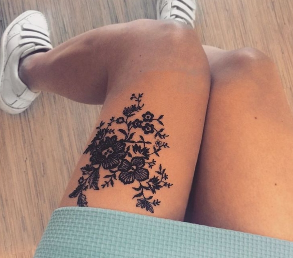Татуировка в виде кружева с ветами на ноге девушки