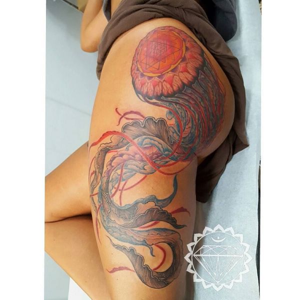 Татуировка медузы в цвете на бедре девушки