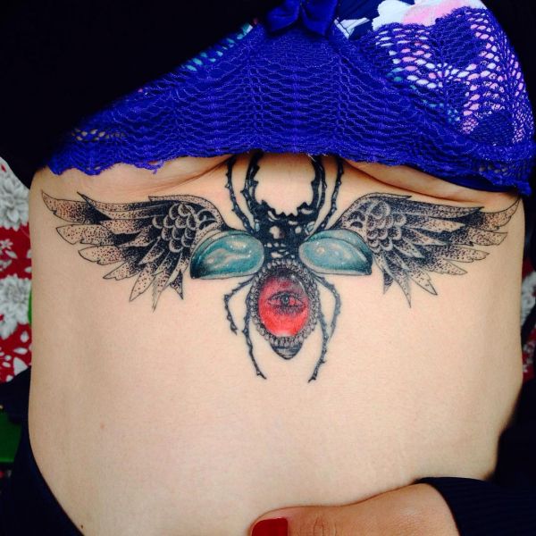 Татуировка большого жука-скарабея на животе девушки