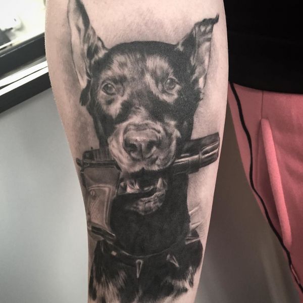 Татуировка собаки доберман с пистолетом с зубах