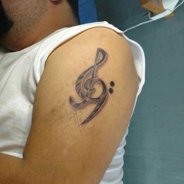 Татуировка в виде скрипичного ключа с нотами на плече парня