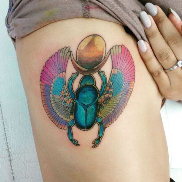 Жук-скарабей сьбоку тела у девушки в виде цветной татуировки