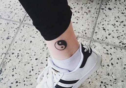 Черно-белый знак инь-янь на ноге девушки