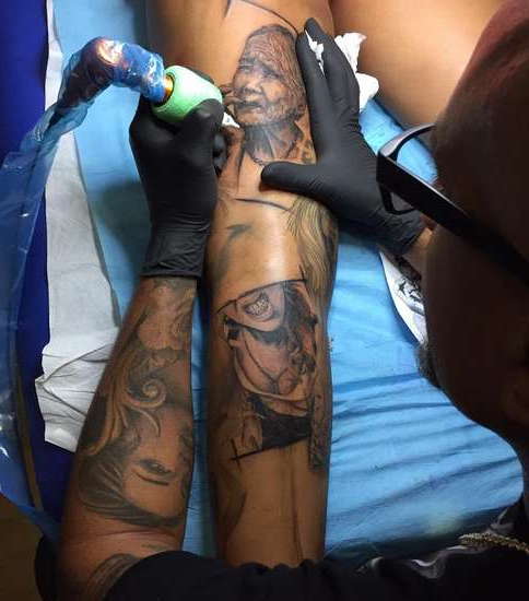 Мастер набивает татуировку на ноге