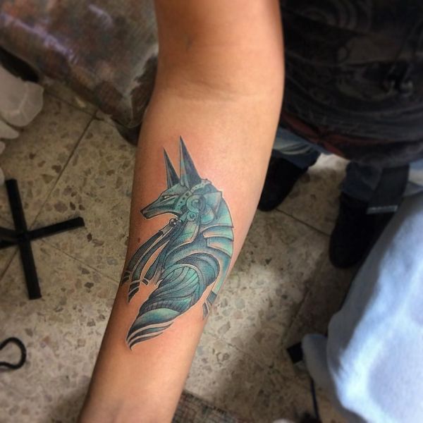Татуировка анубис с голубым оттенком на руке