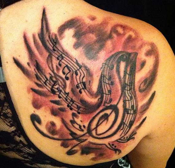 Музыкальная татуировка на лопатке в виде воробья с нотами и скрипичным ключом