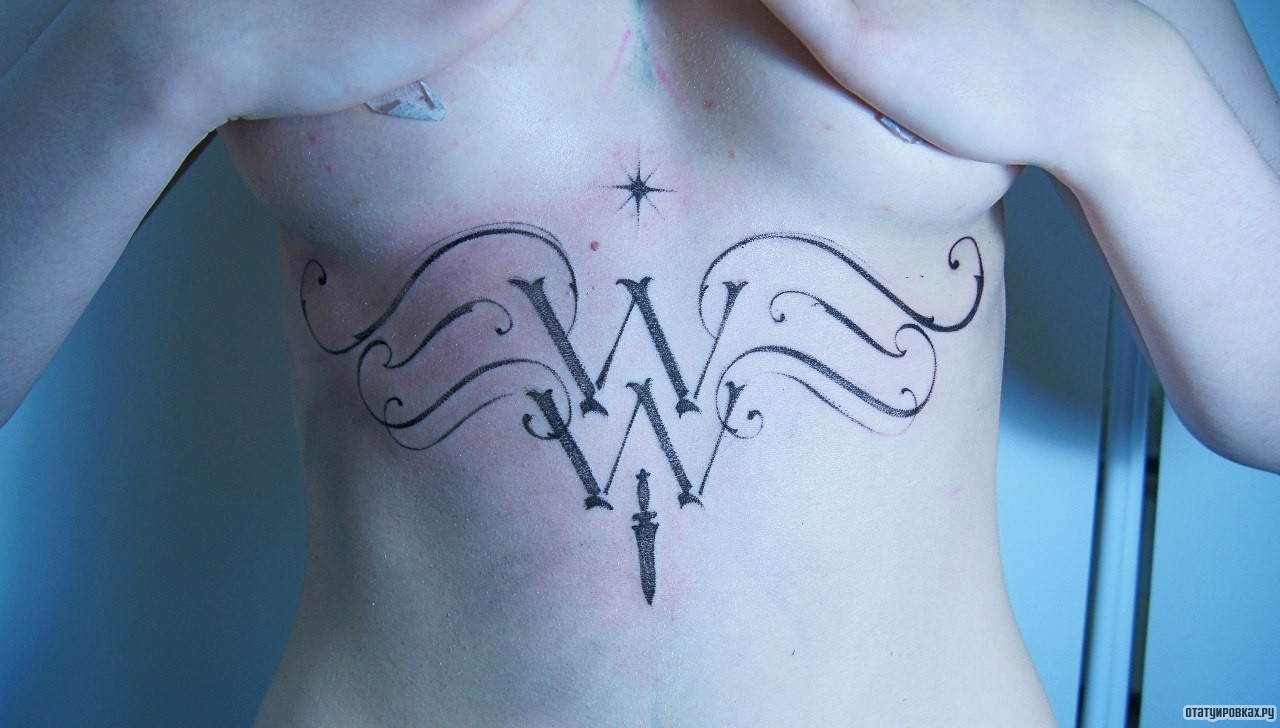 Фотография татуировки под названием «Надпись с узорами и кинжалом»