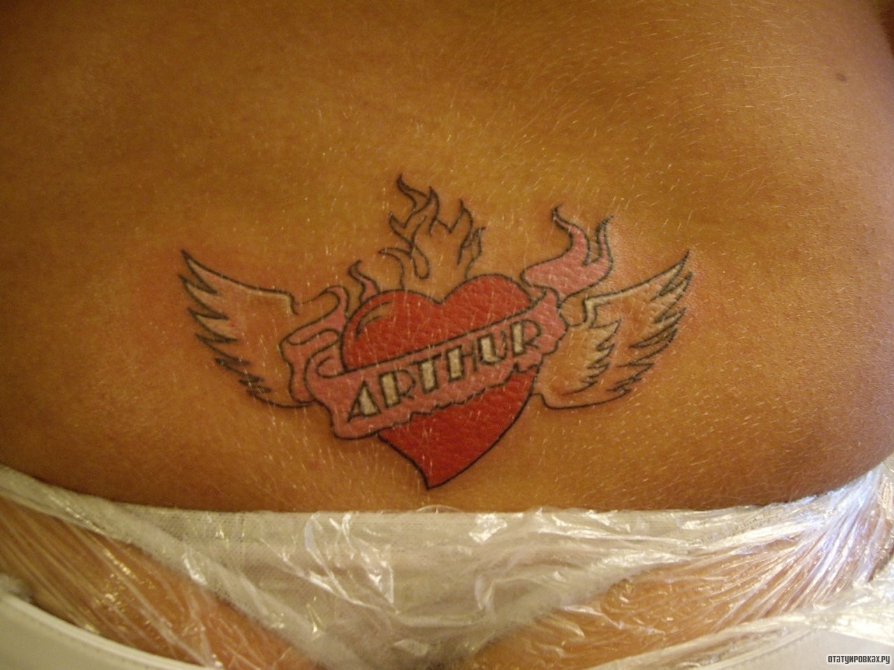 Фотография татуировки под названием «Сердце с крыльями и надпись»