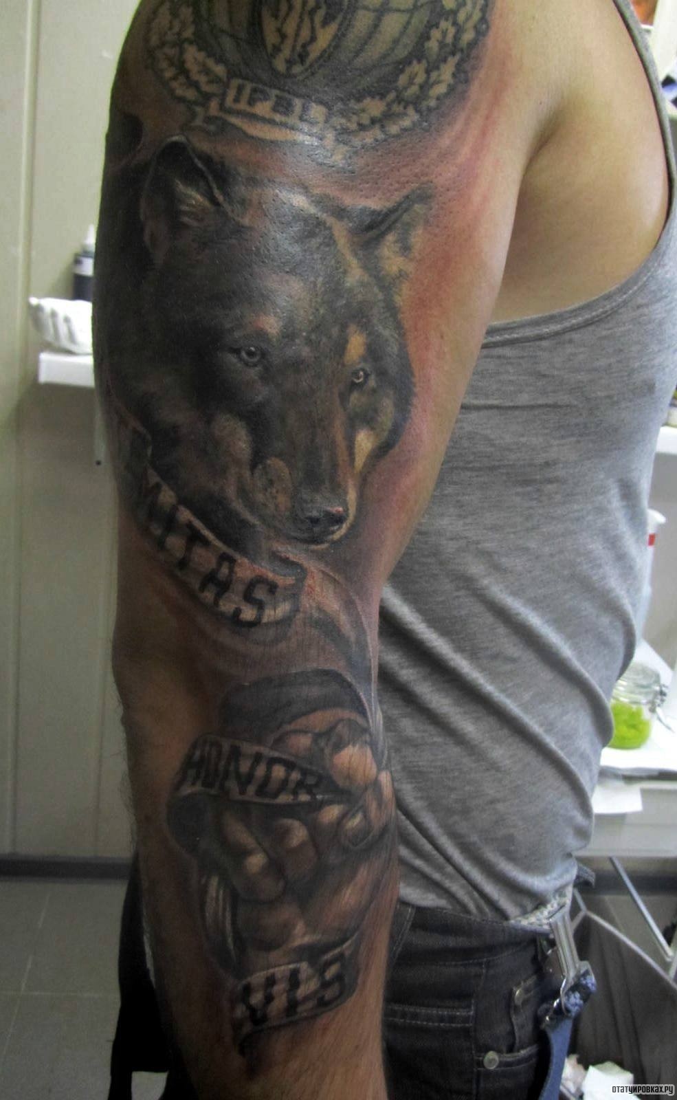 Фотография татуировки под названием «Волк, кулак, надписи»