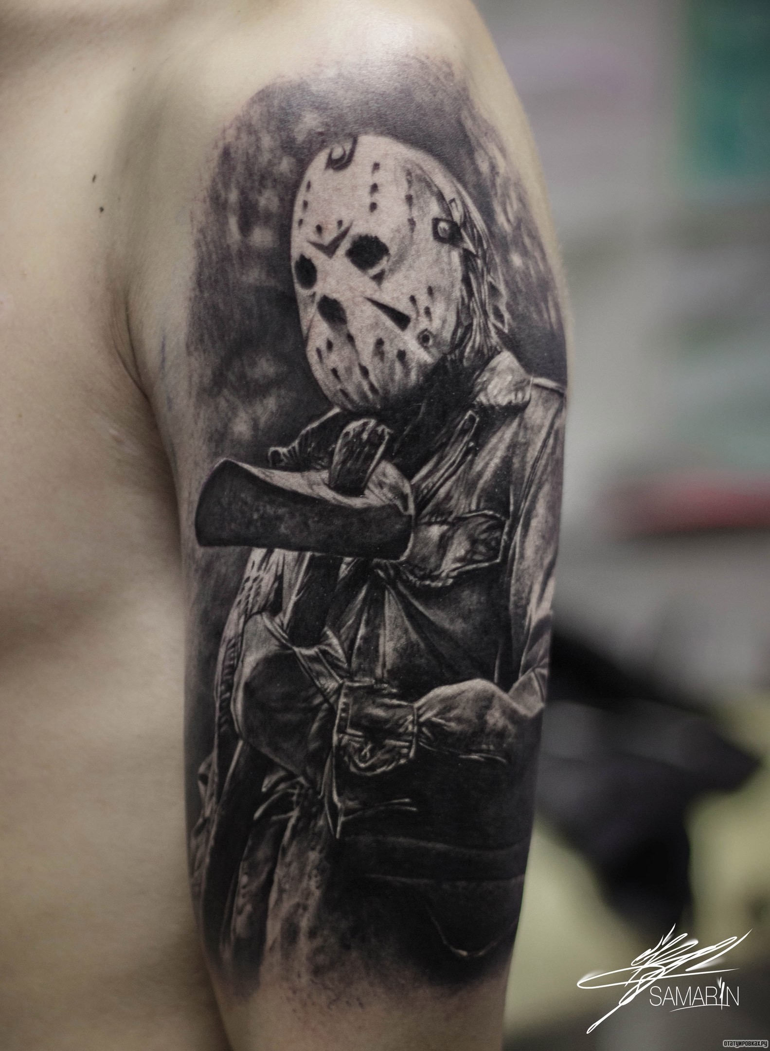 Фотография татуировки под названием «Человек в маске с топором на плече»