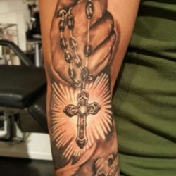 Крест на цепочке в руке на предплечье, на плече