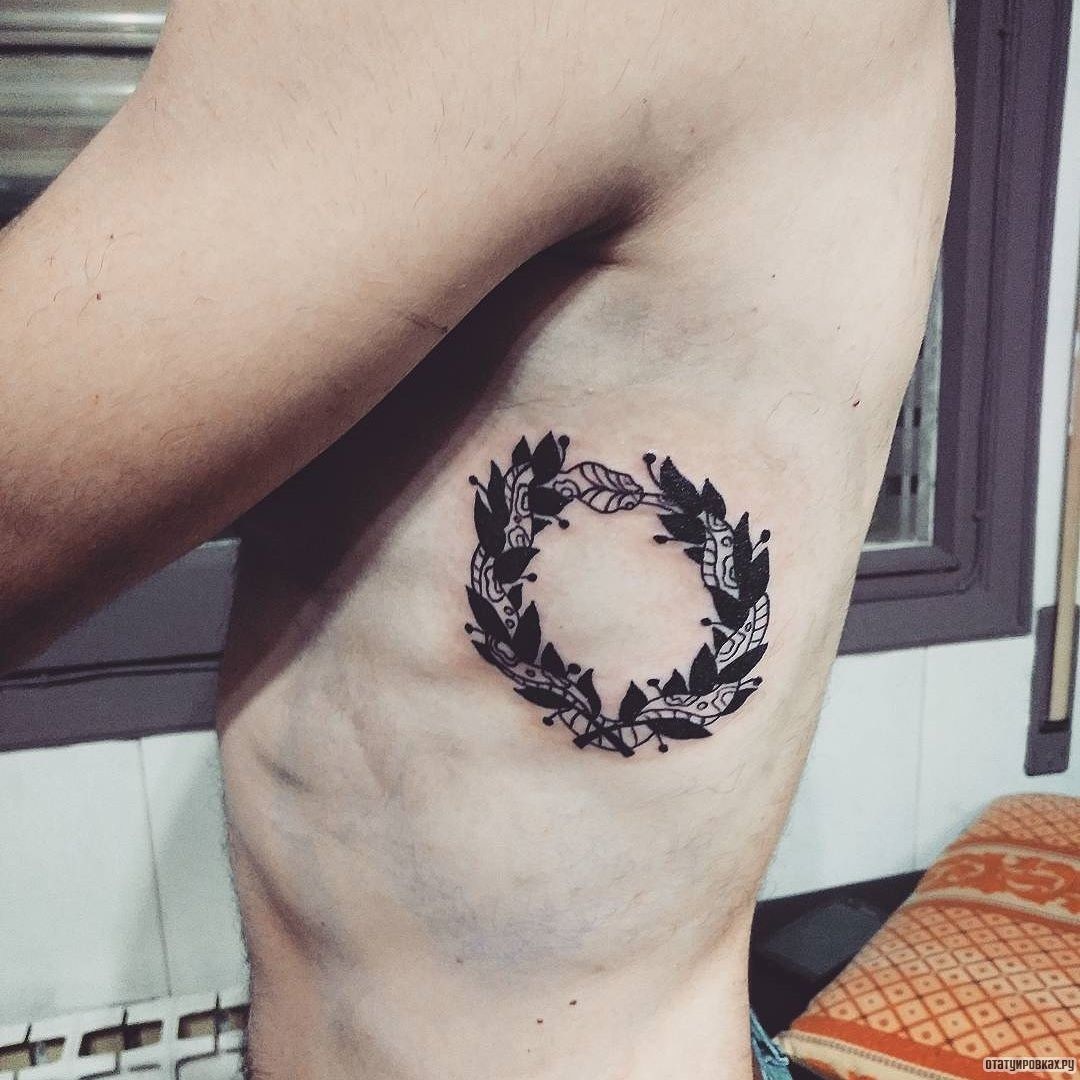 Фотография татуировки под названием «Уроборос в виде узора из змеи и листьев»