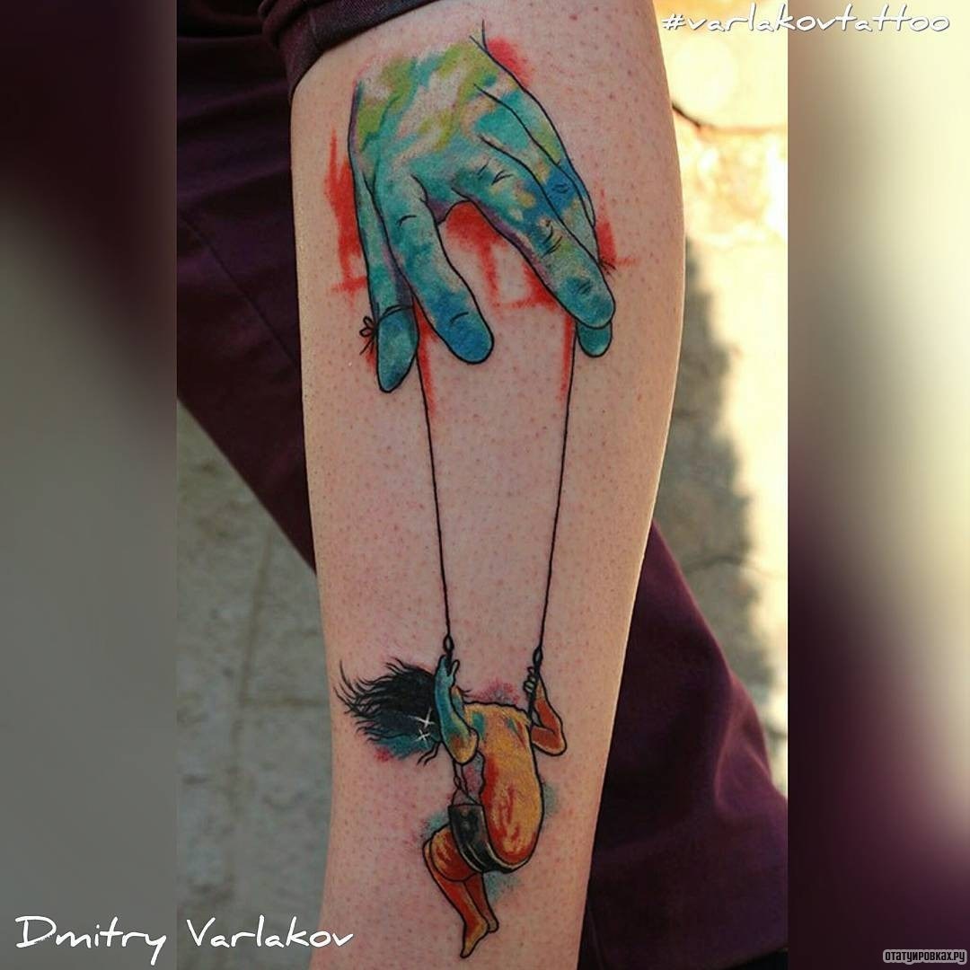 Фотография татуировки под названием «Рука управляет человеком на качелях»