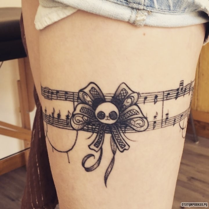 Фотография татуировки под названием «Подвязка в виде нот»