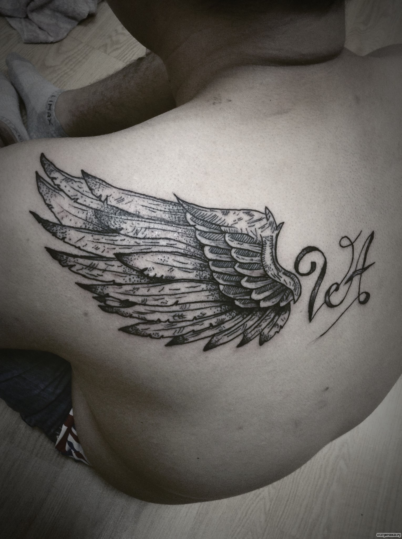 Фотография татуировки под названием «Крыло с надписью»