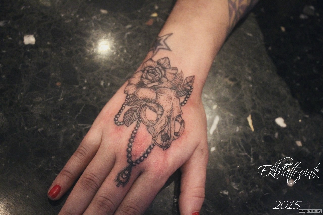 Фотография татуировки под названием «Цветок, череп, подвеска»