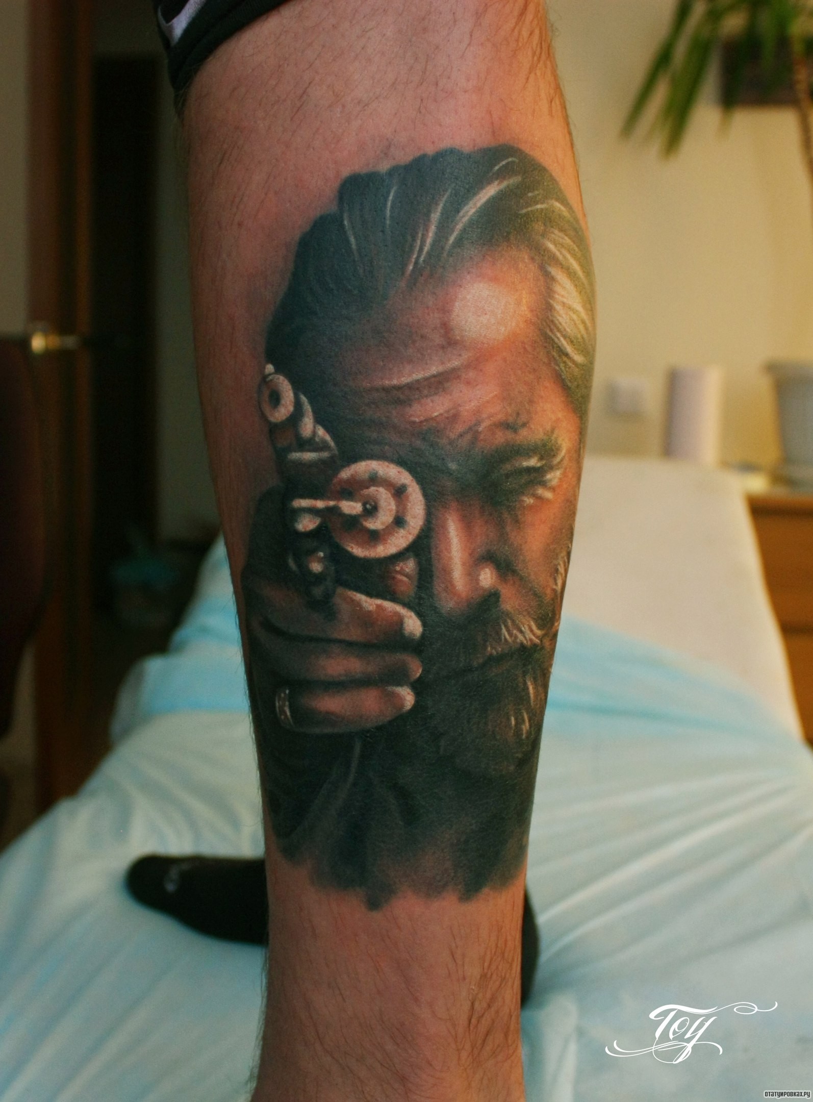 Фотография татуировки под названием «Человек метится их пистолета»