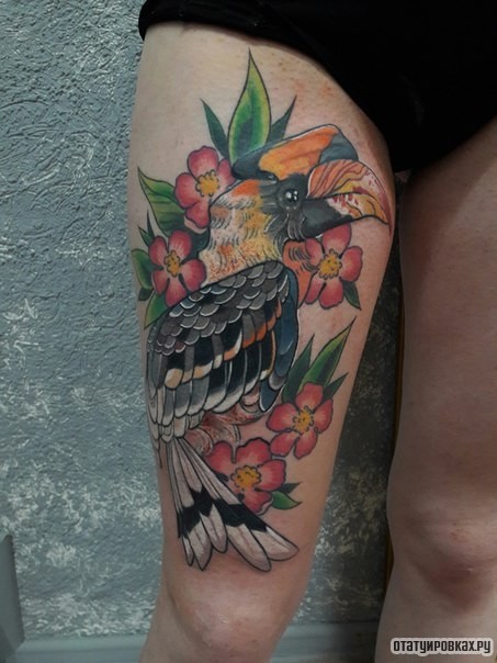 Фотография татуировки под названием «Попугай в цветах на бедре девушки»