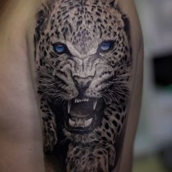 Тату ягуар с голубыми гланами на плече