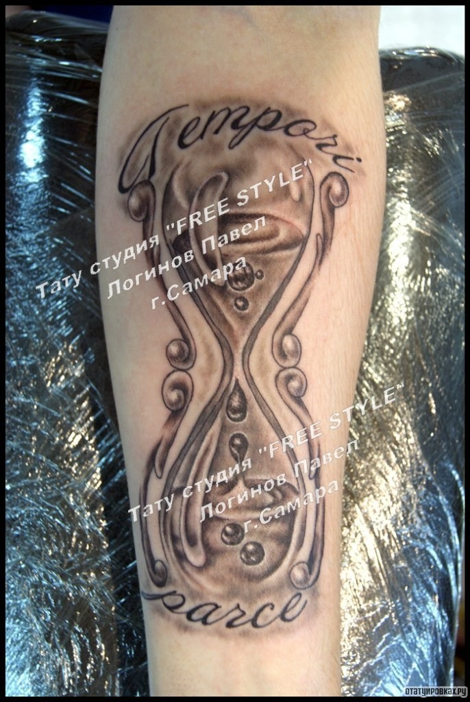 Фотография татуировки под названием «Песочные часы с надписью на предплечье»